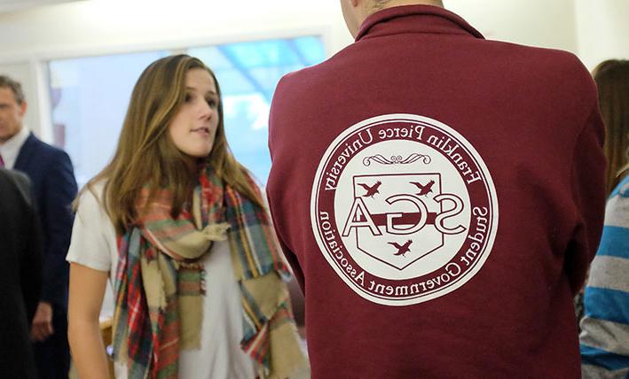 Student talks to person with SGA on the back of their t-shirt